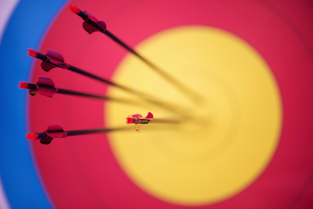 photograph of multiple arrows in target's bullseye