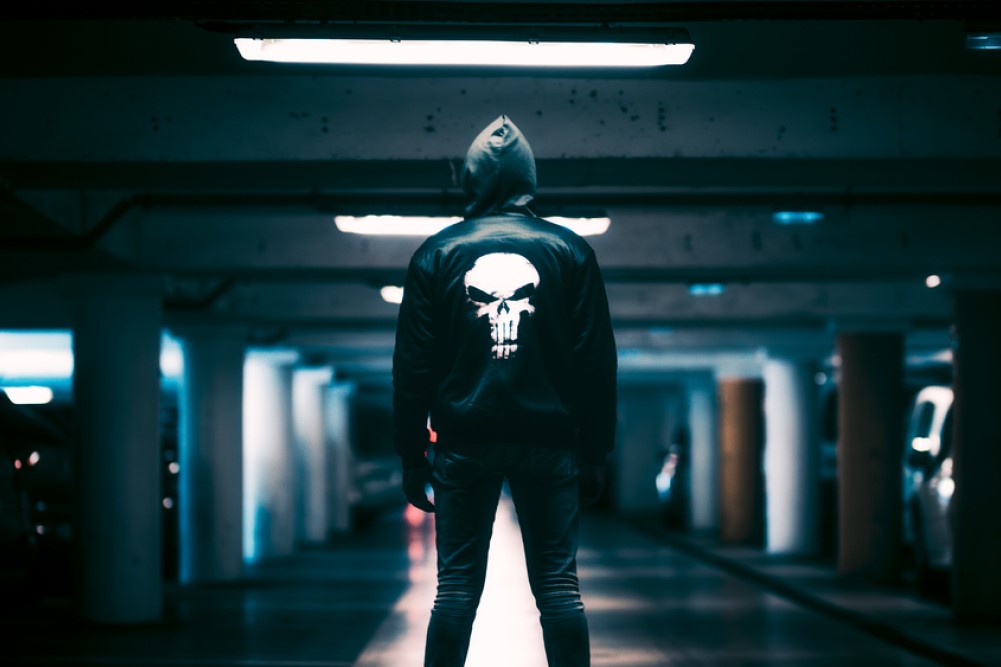photograph of man in dark parking garage with Punisher jacket
