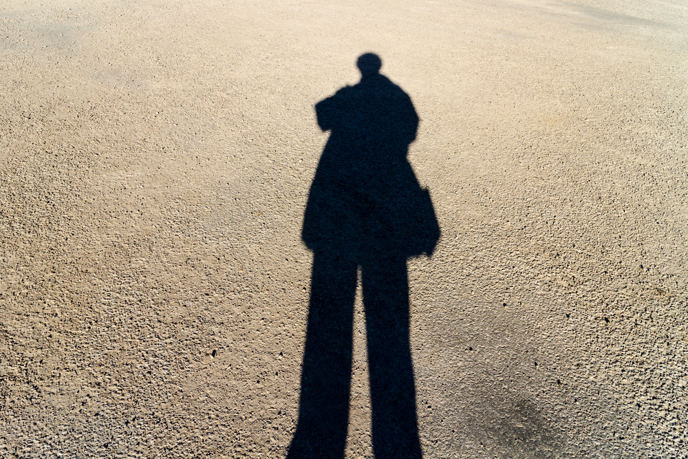 photograph of elongated shadow of person on paved road