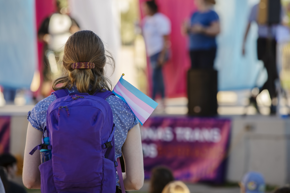 photograph of youth holding small Trans Support Flag at rally