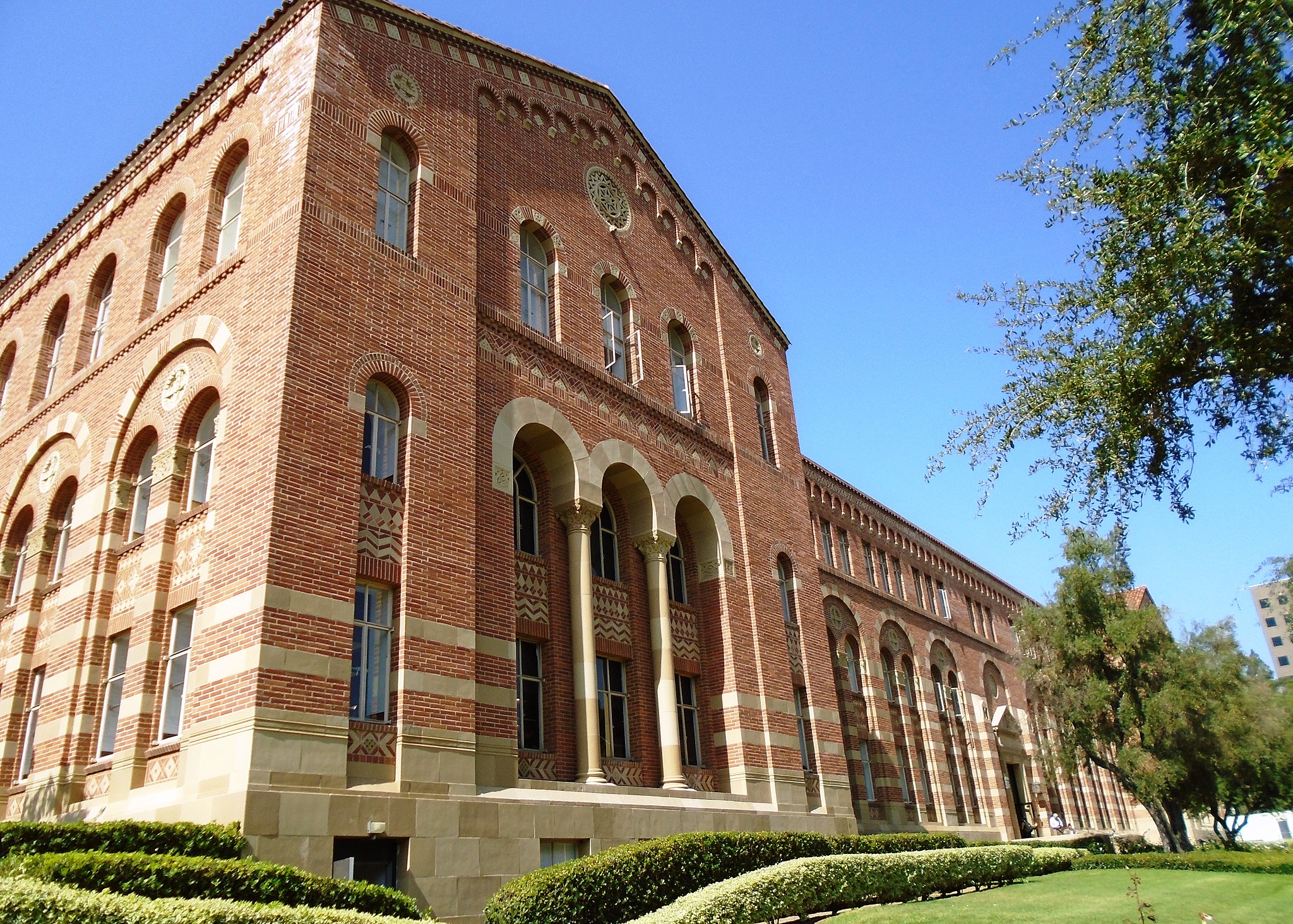 Color photograph of Haines Hall at UCLA, a large red brick building with lots of Romanesque arches