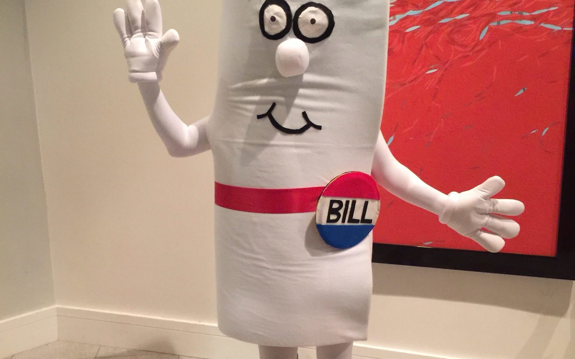 Color photograph of a person in a school hallway dressed in a Schoolhouse Rock "I'm a Bill" costume
