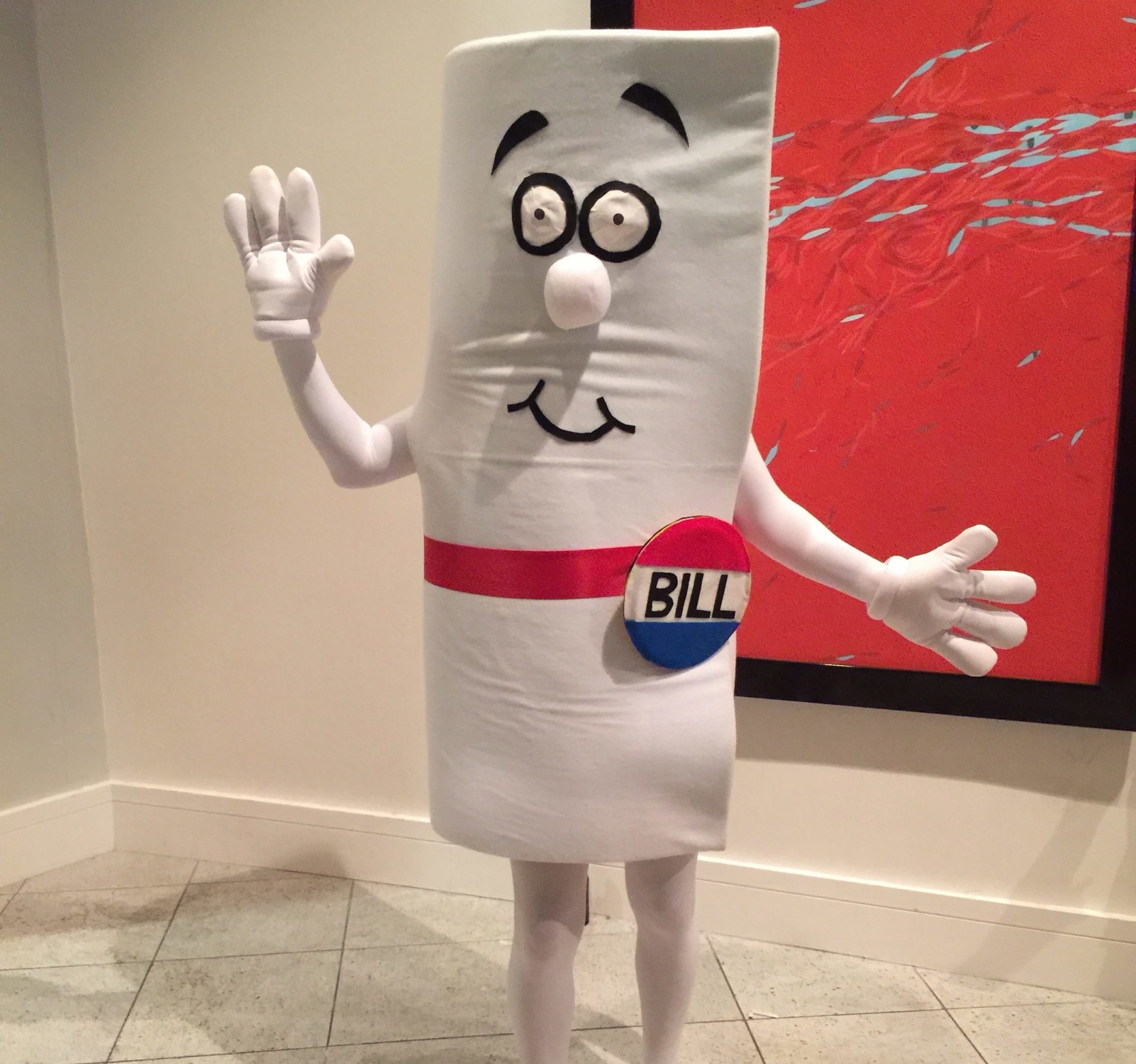 Color photograph of a person in a school hallway dressed in a Schoolhouse Rock "I'm a Bill" costume