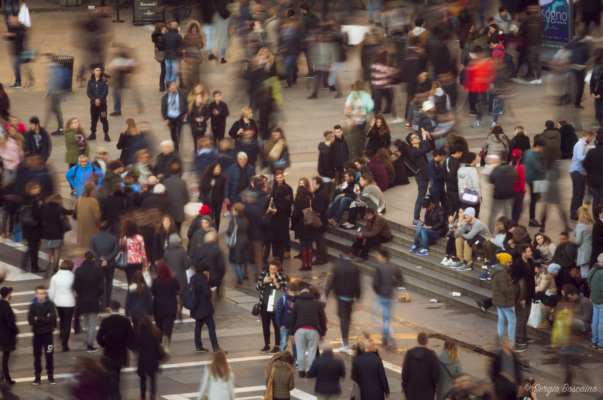 Birds-eye view of a crowd of people. Some people are in focus and others are blurred.