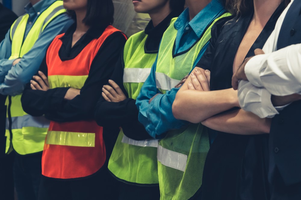 photograph of workers standing together, arms crossed