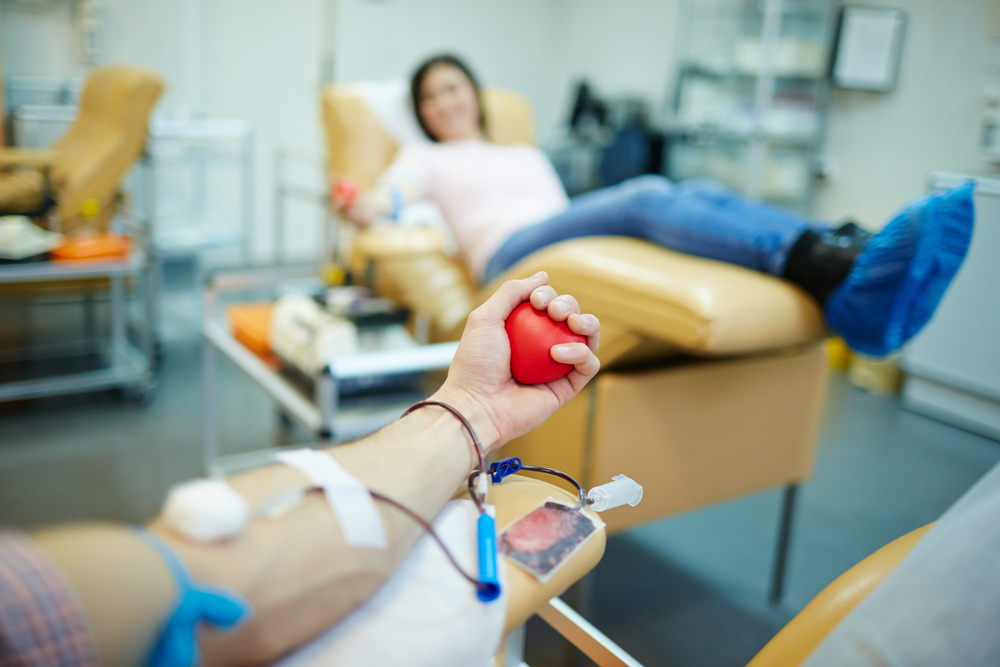POV photograph of blood donor with another patient in blurry background