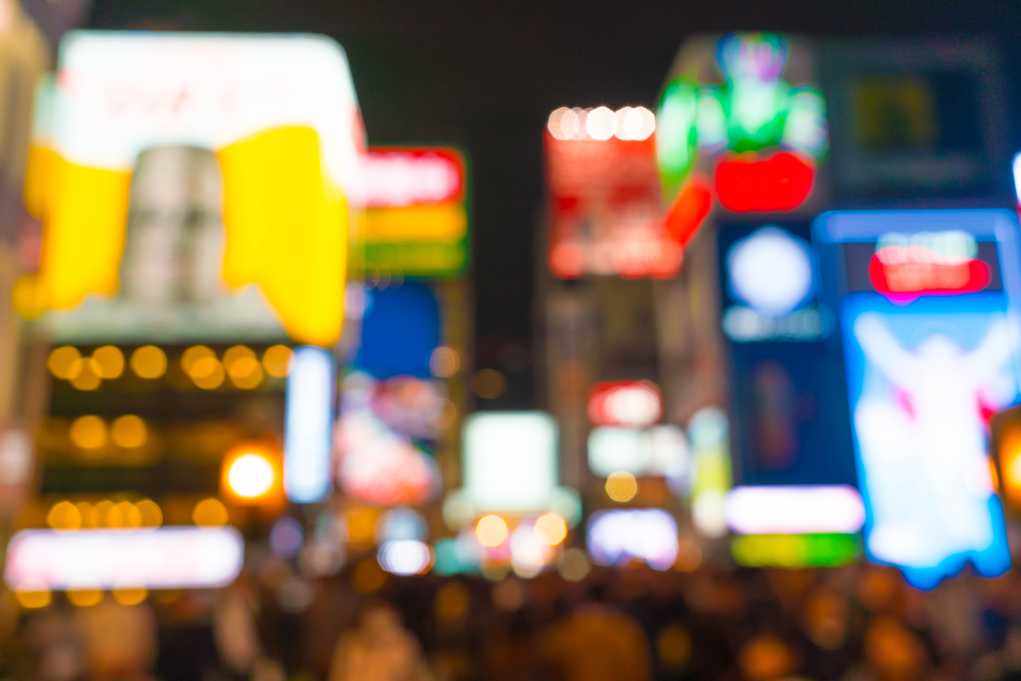 blurred photograph of crowd below large interactive billboards