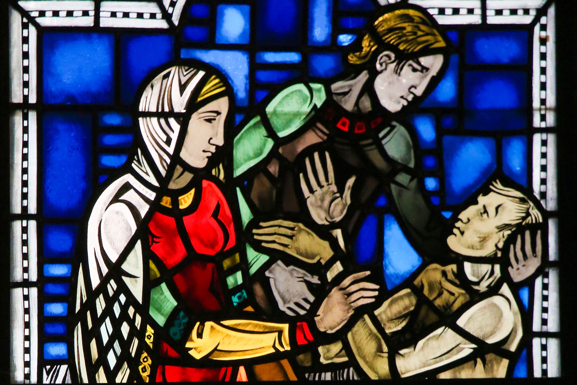 stained glass depicting two figured displaying mercy to dying man