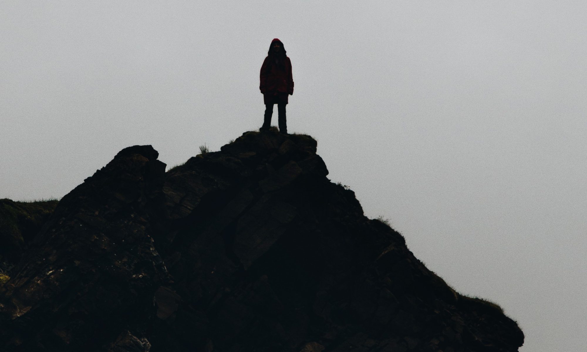 photograph of silhouetted woman on cliff