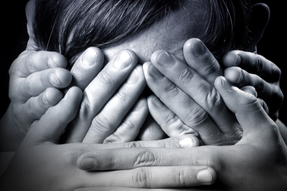 black and white photograph of child with hands over mouth, eyes, and ears