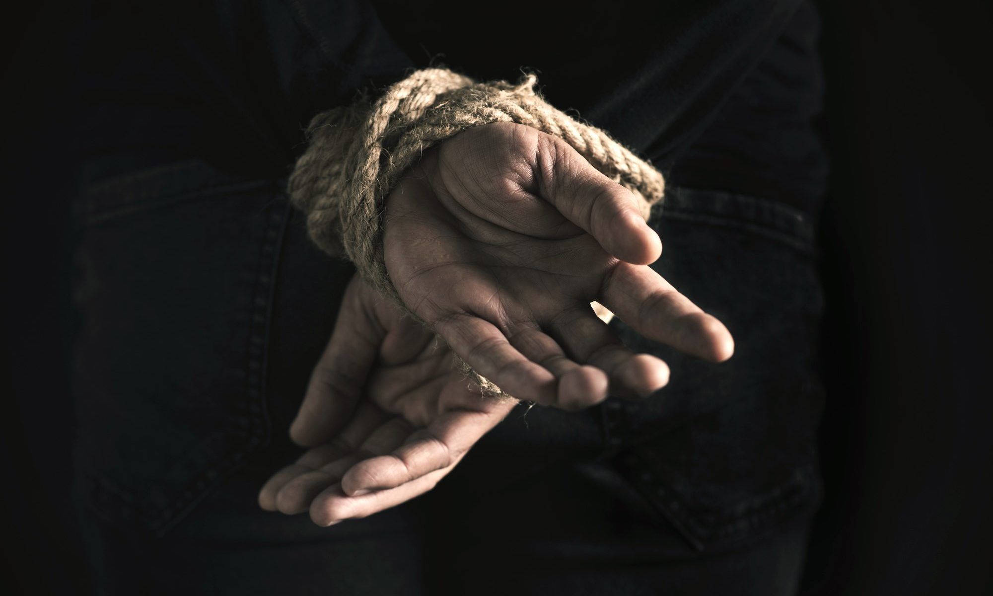 photograph of hands tied behind man's back