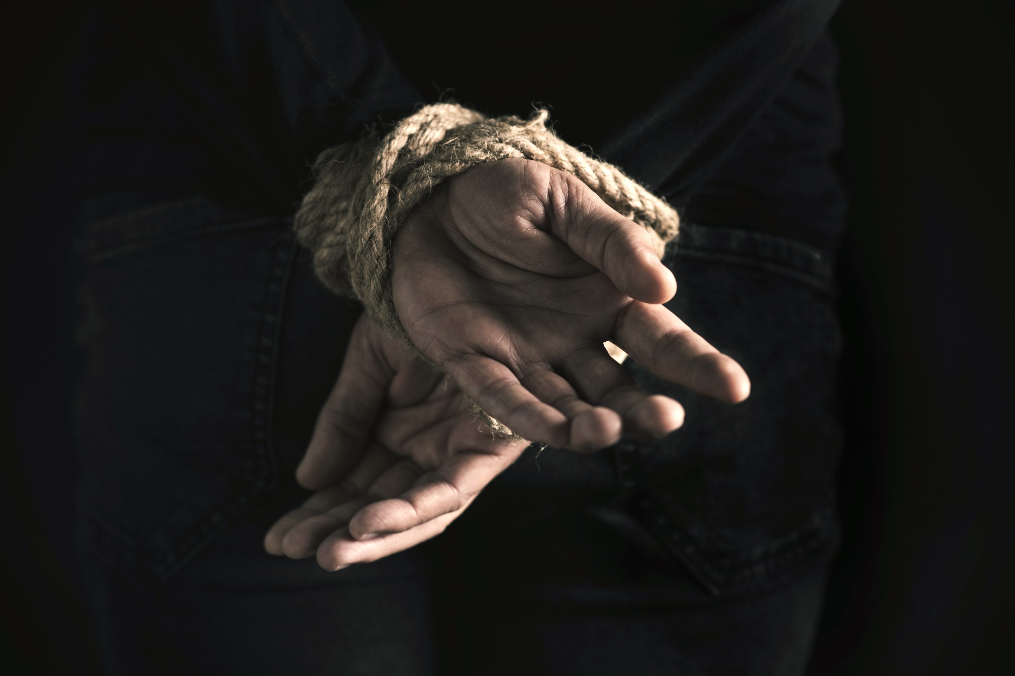 photograph of hands tied behind man's back