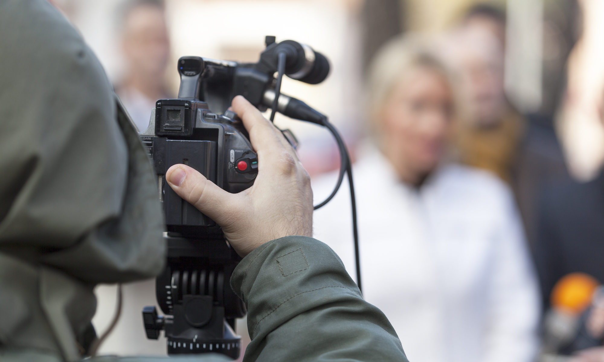 photograph of cameraman filming group on the street