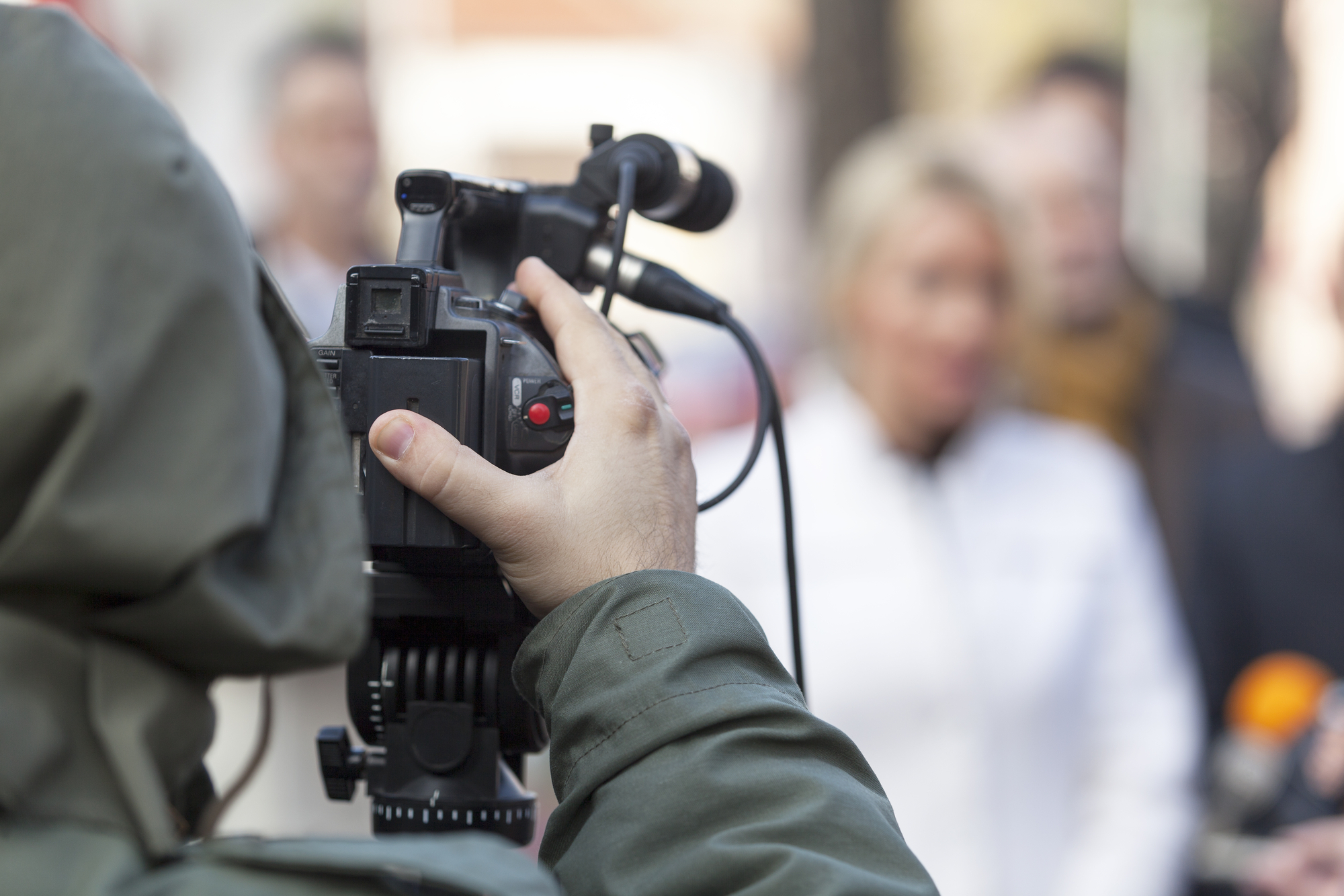 photograph of cameraman filming group on the street