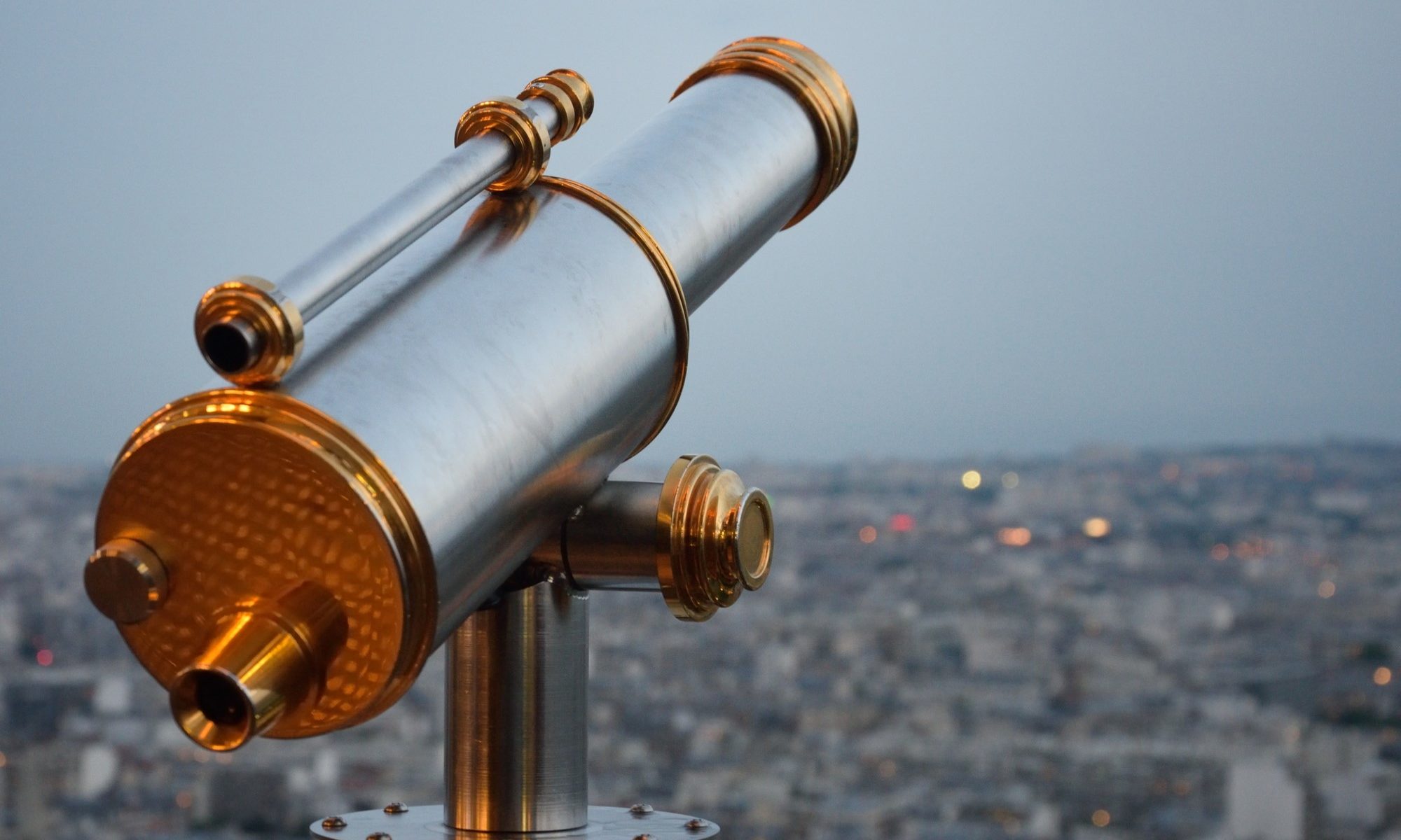 photograph of telescope pointed above the lights of the city