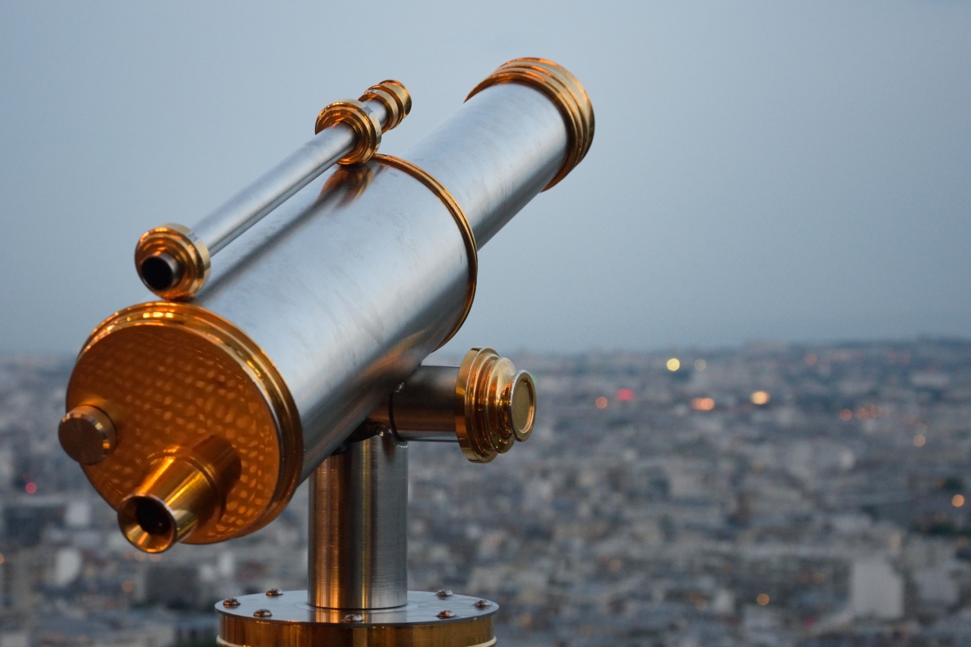 photograph of telescope pointed above the lights of the city