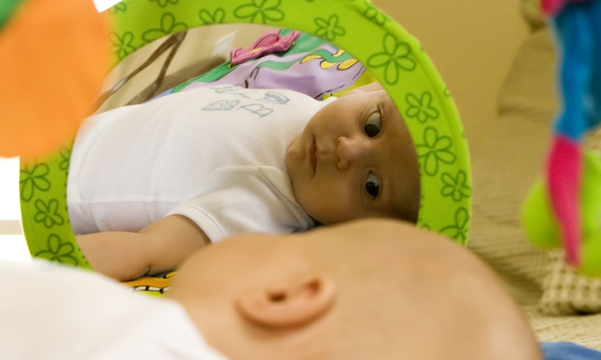photograph of baby looking at self in mirror