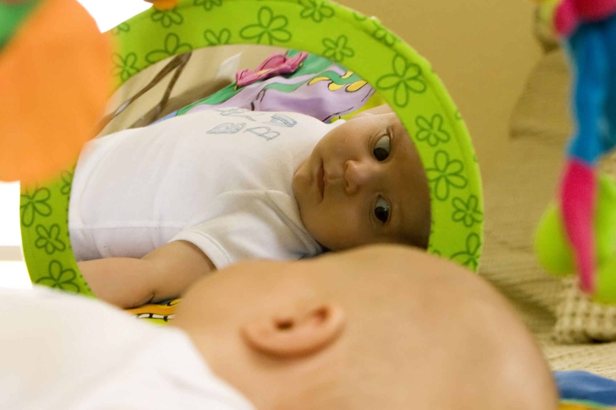 photograph of baby looking at self in mirror