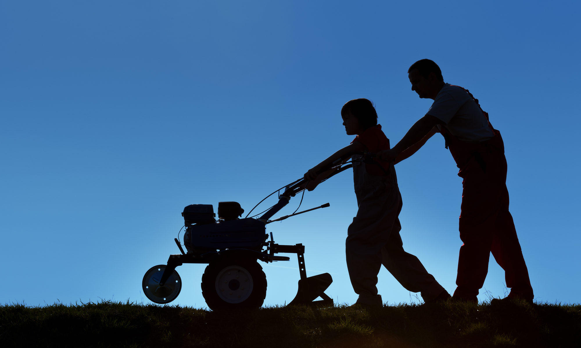 photograph of father and son silhouette working tiller