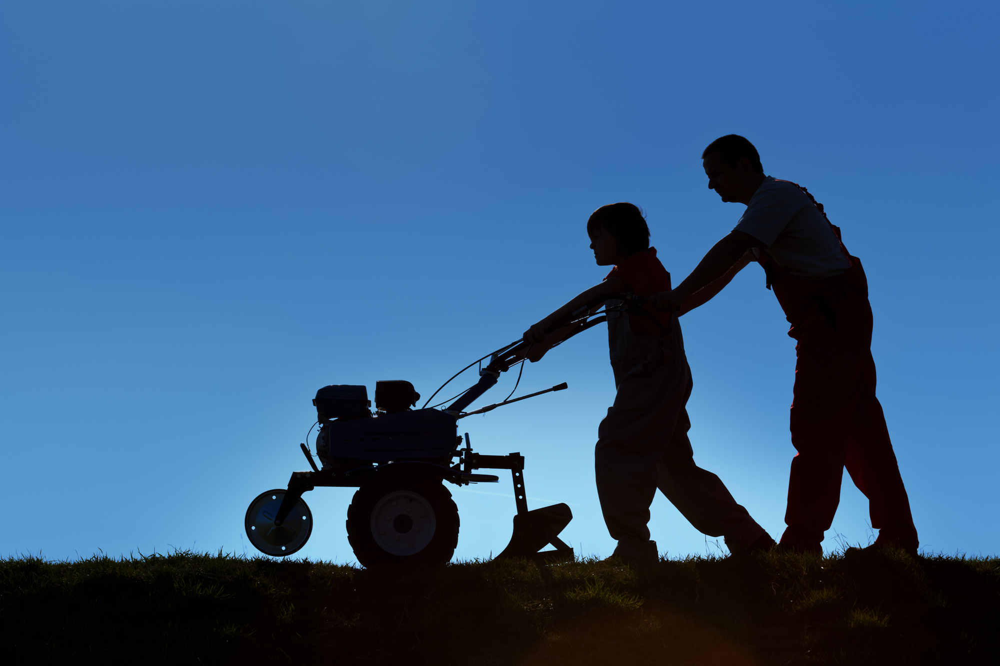 photograph of father and son silhouette working tiller