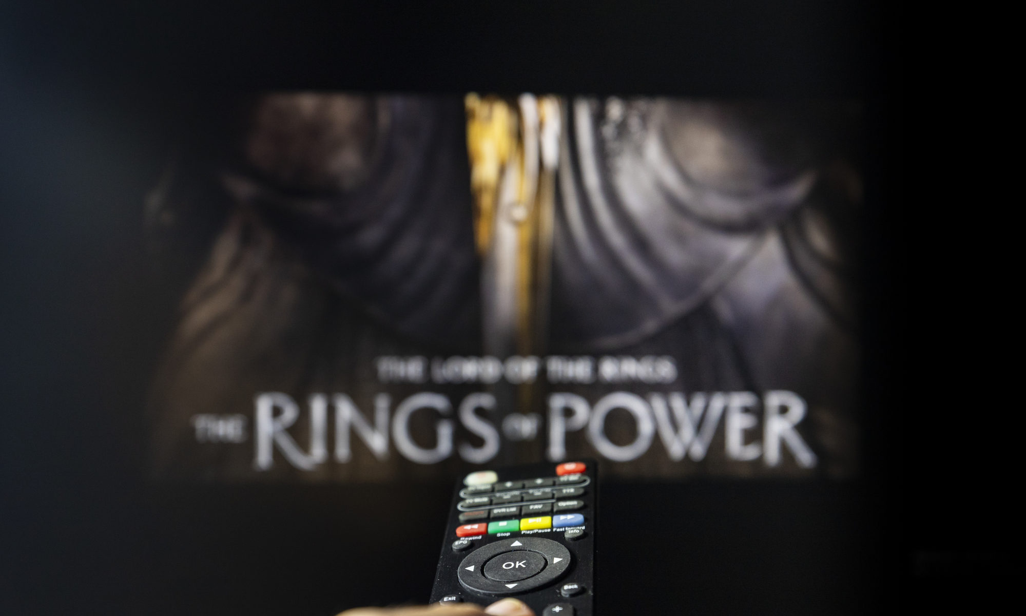 photograph of The Rings of Power TV series on TV with remote control in hand