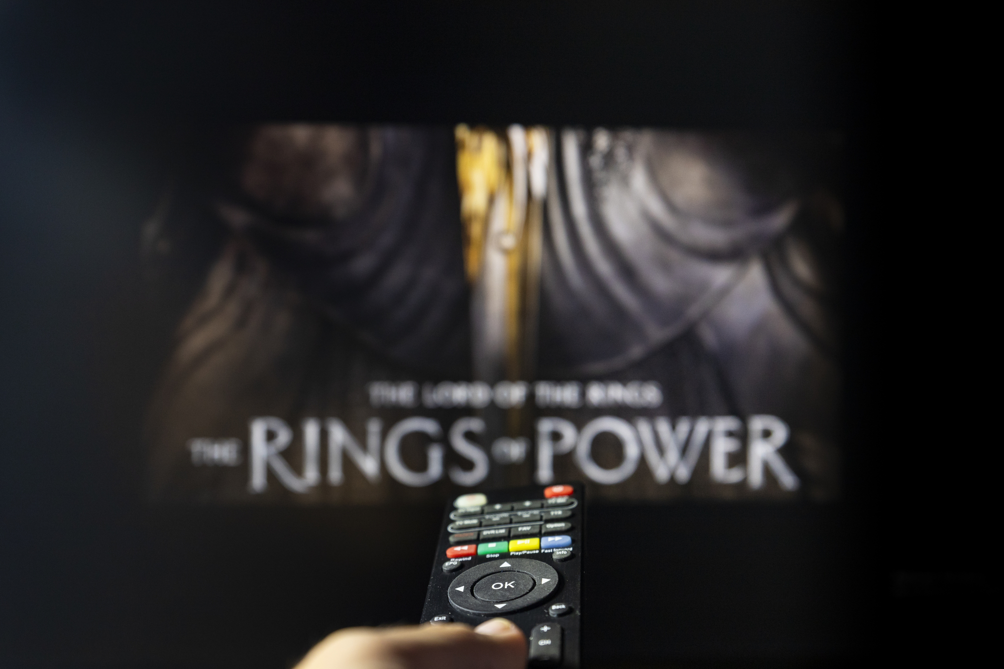 photograph of The Rings of Power TV series on TV with remote control in hand