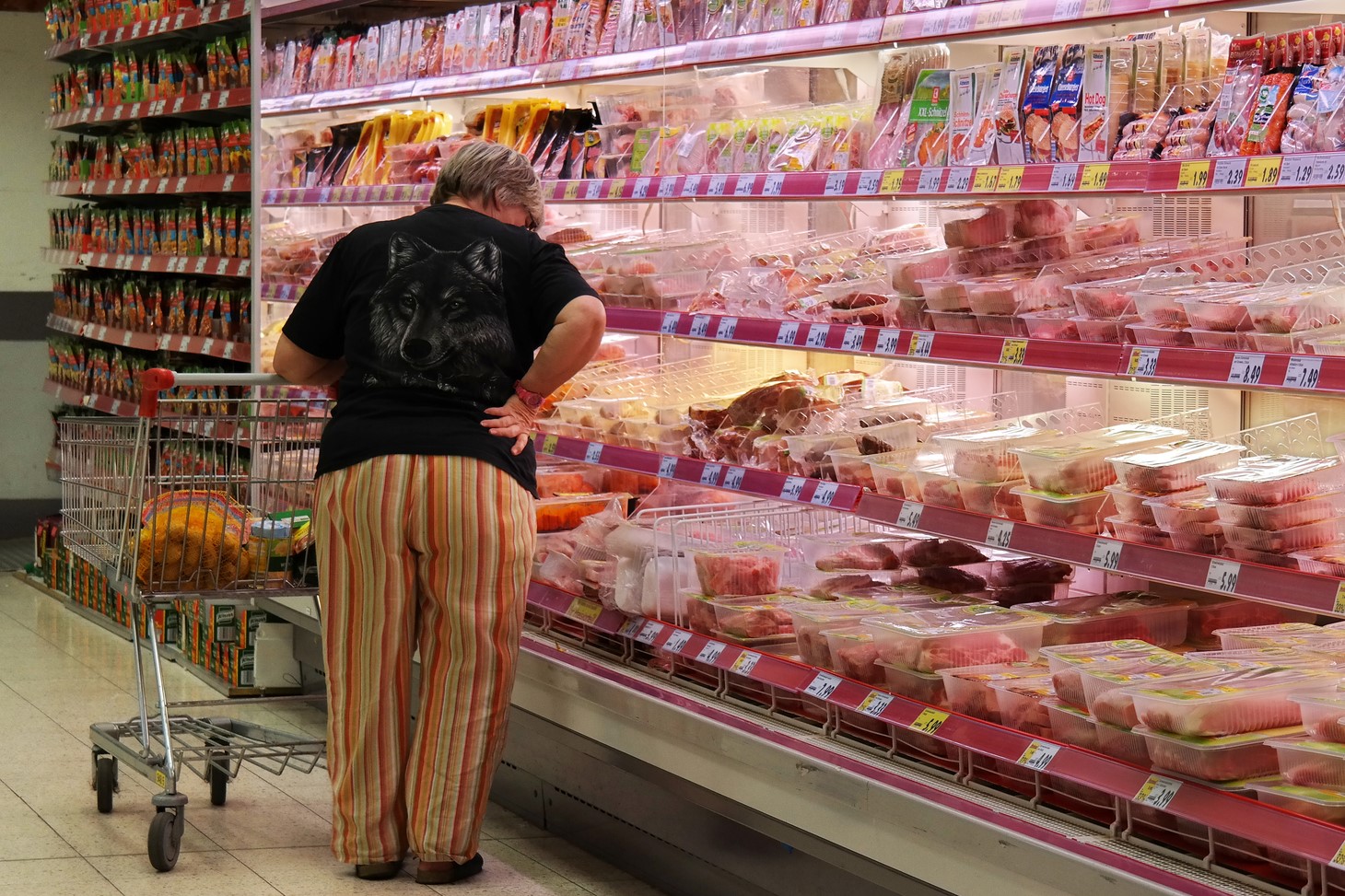 photograph of grocery shopper debating purchase at meat aisle