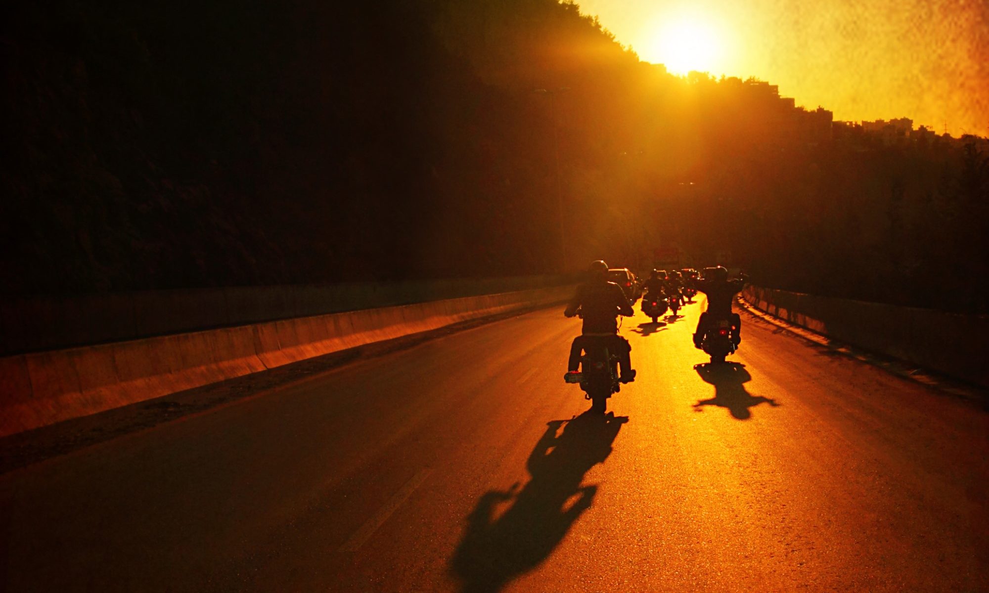 photograph of motorcycle group riding as sun sets
