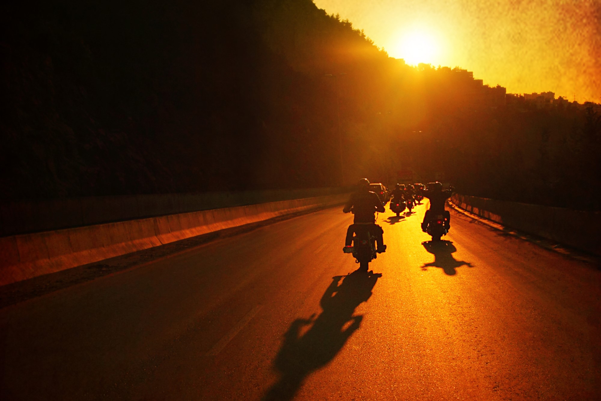 photograph of motorcycle group riding as sun sets