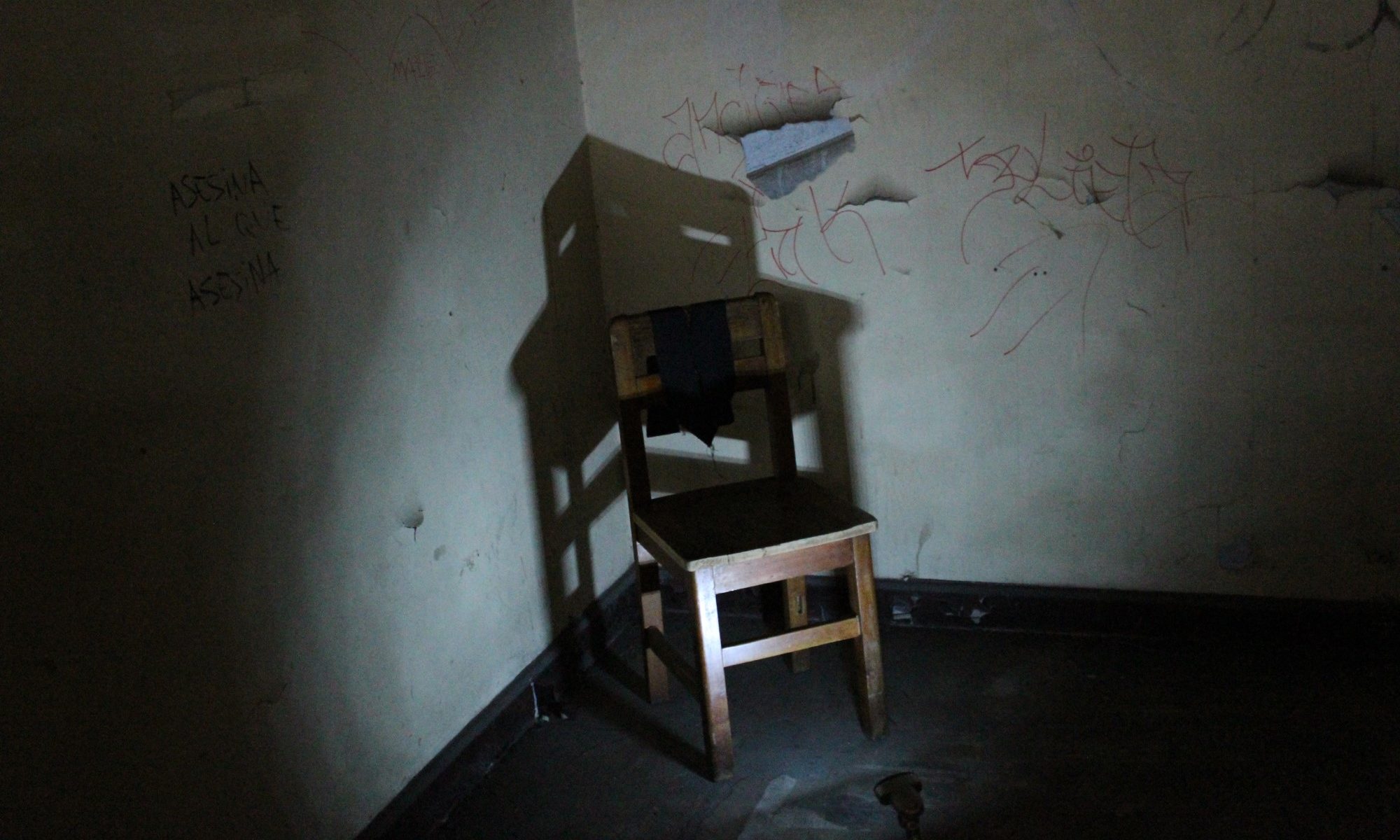 photograph of chair against wall in dark room