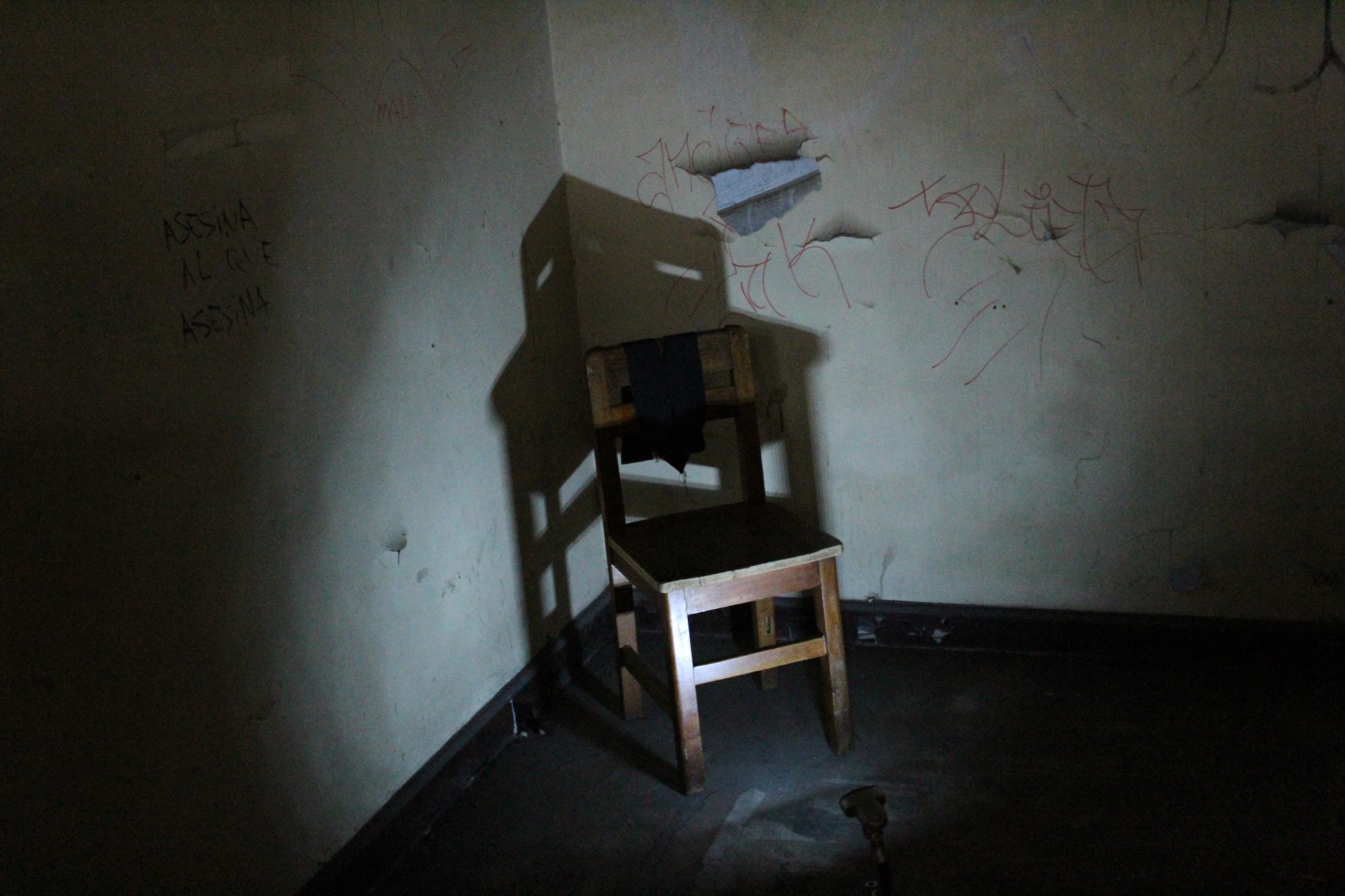 photograph of chair against wall in dark room