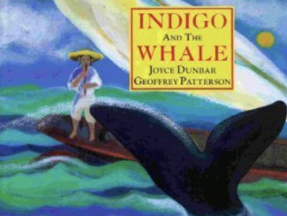 Cover illustration of Joyce Dunbar's book Indigo and the Whale featuring a young boy sitting on a boat playing music. The tail of a whale is sticking out of the water in front of the boat.