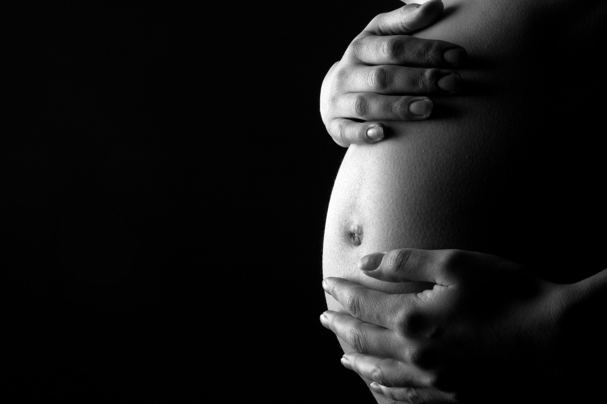 black and white photograph of pregnant person holding stomach