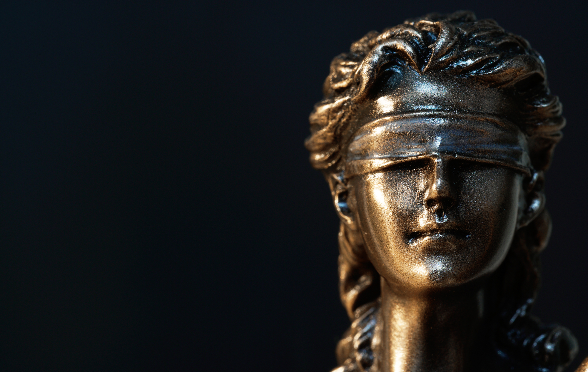 close-up photograph of Lady Justice statue's blindfolded face