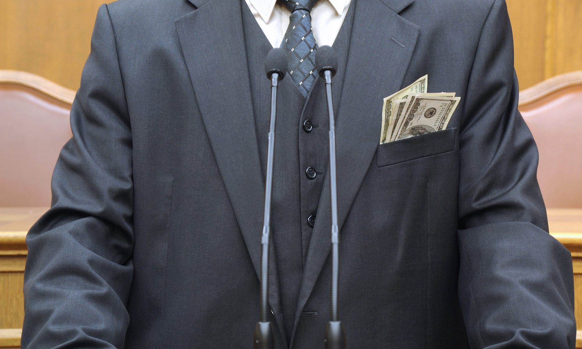 photograph of empty suit at podium with money hanging out of jacket pocket
