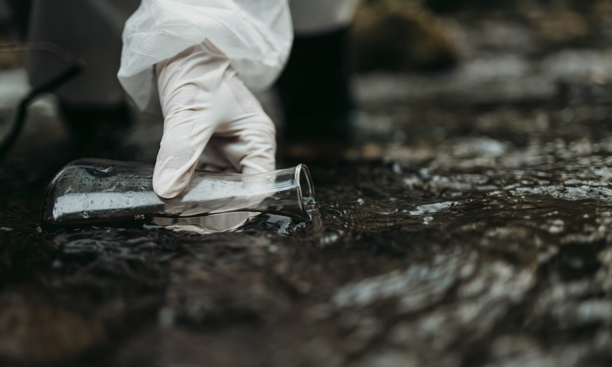 photograph of gloved hand taking water sample