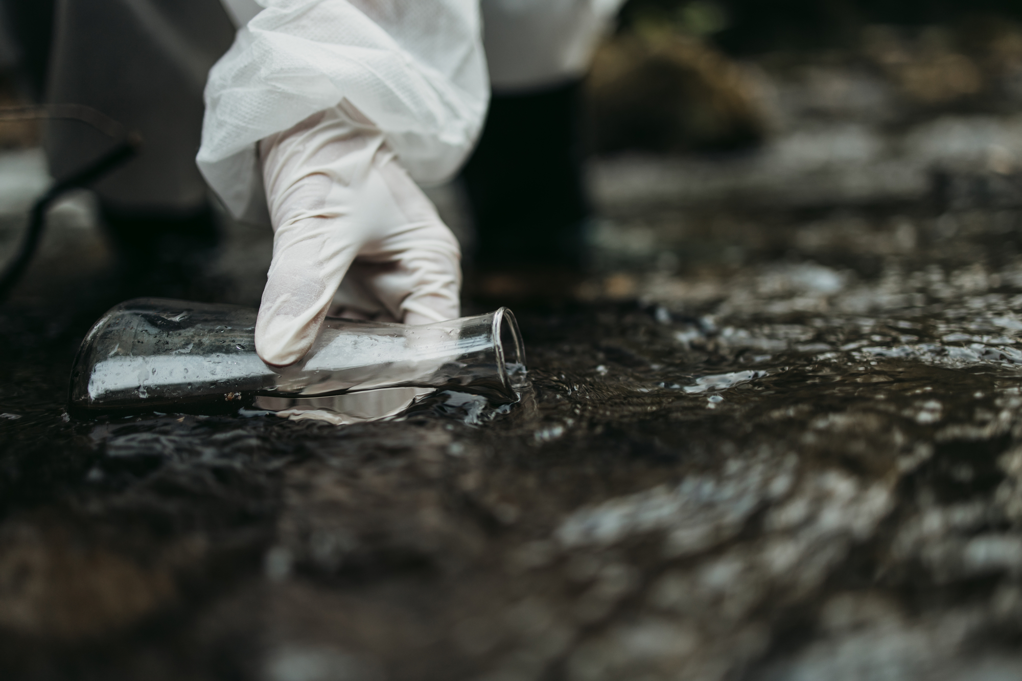 photograph of gloved hand taking water sample