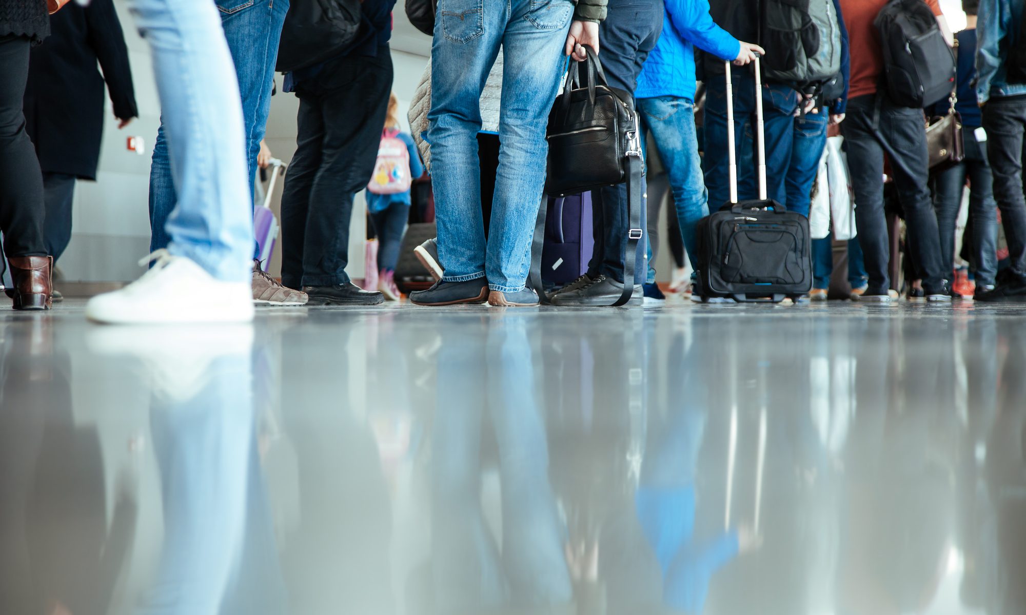 photograph of line of people with luggage at airport