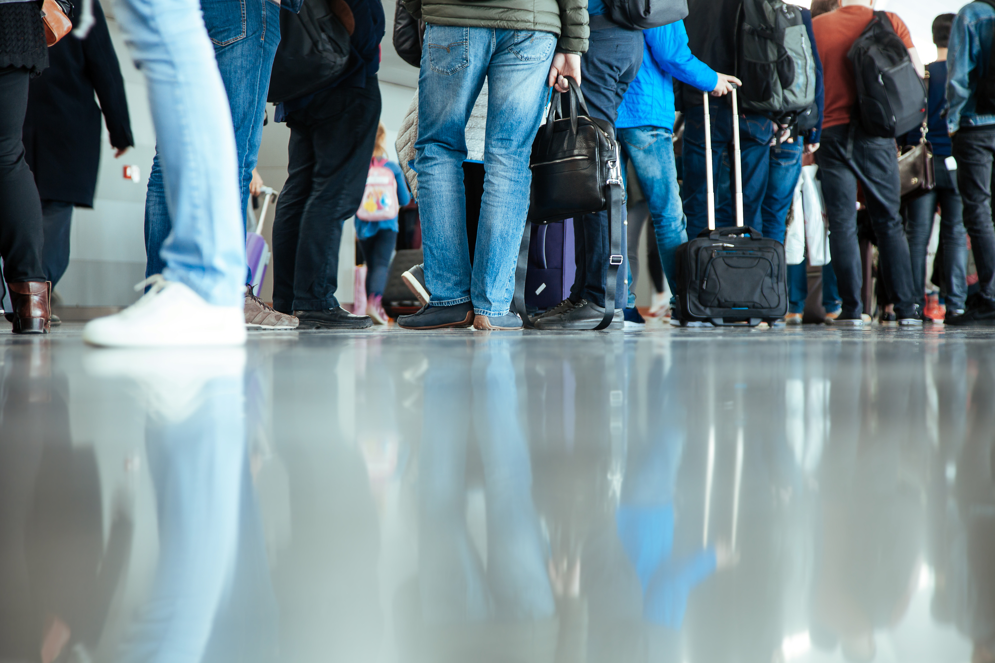 photograph of line of people with luggage at airport