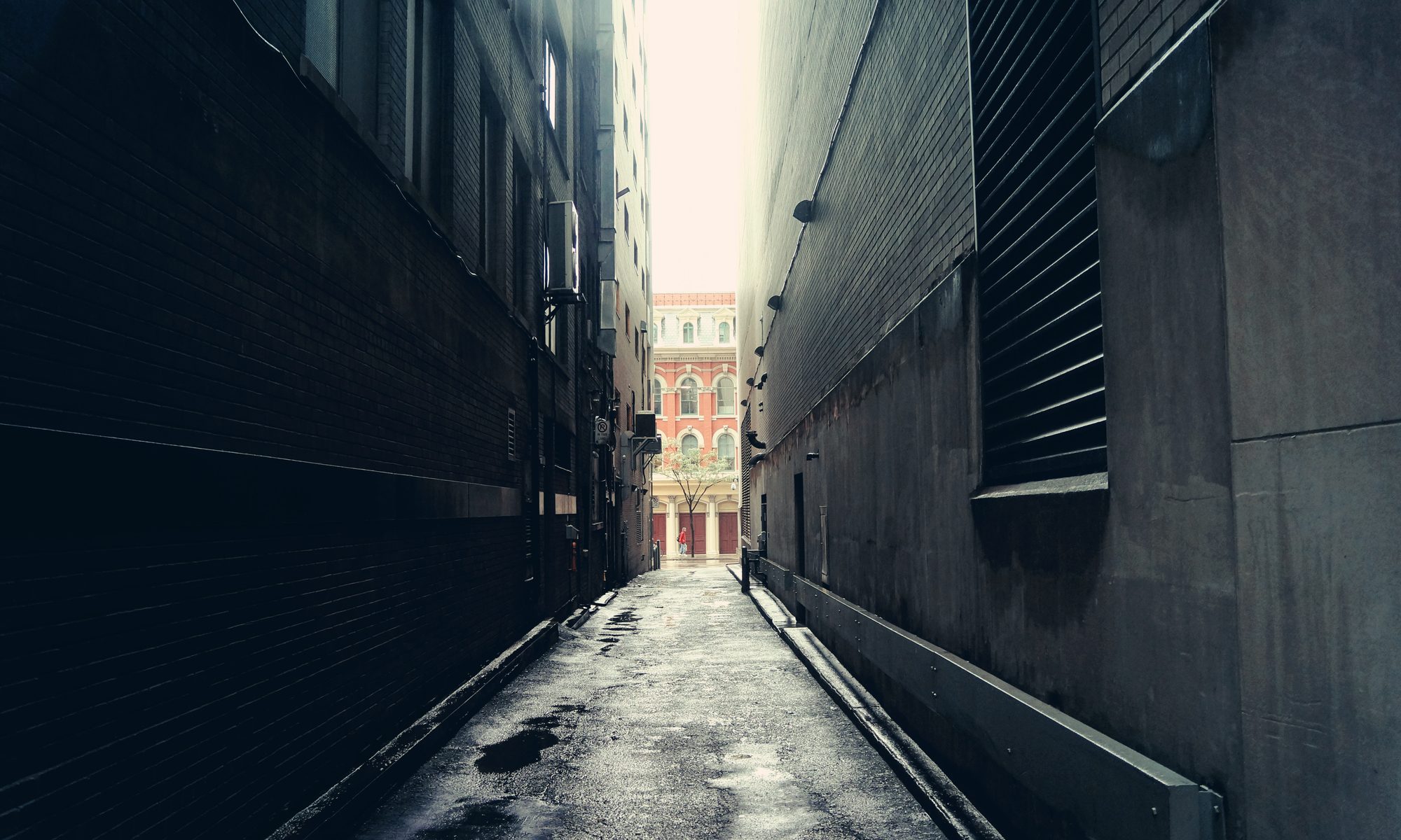 photograph of dark alley with sunlit street in background