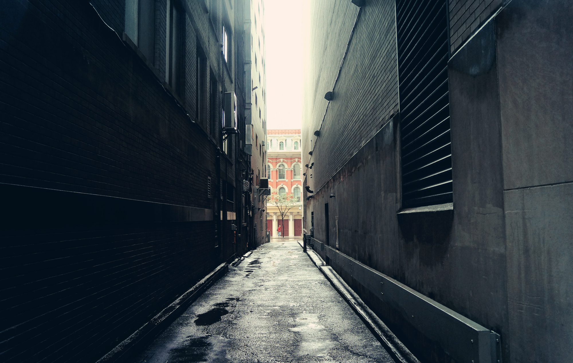 photograph of dark alley with sunlit street in background