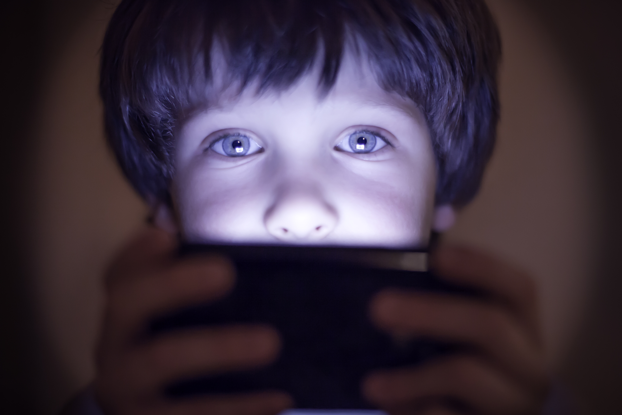 photograph of small child playing on smartphone