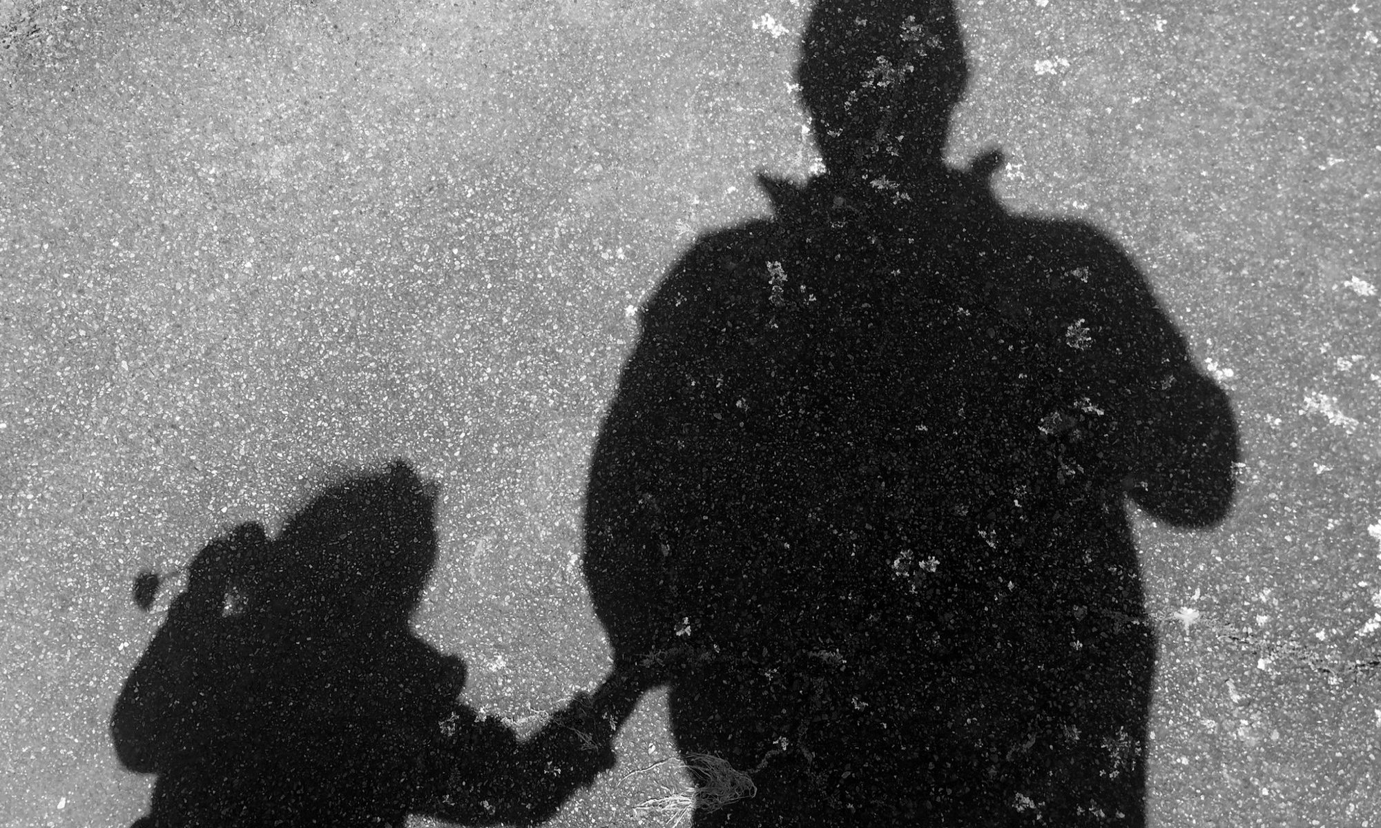photograph of child and parent shadow on asphalt
