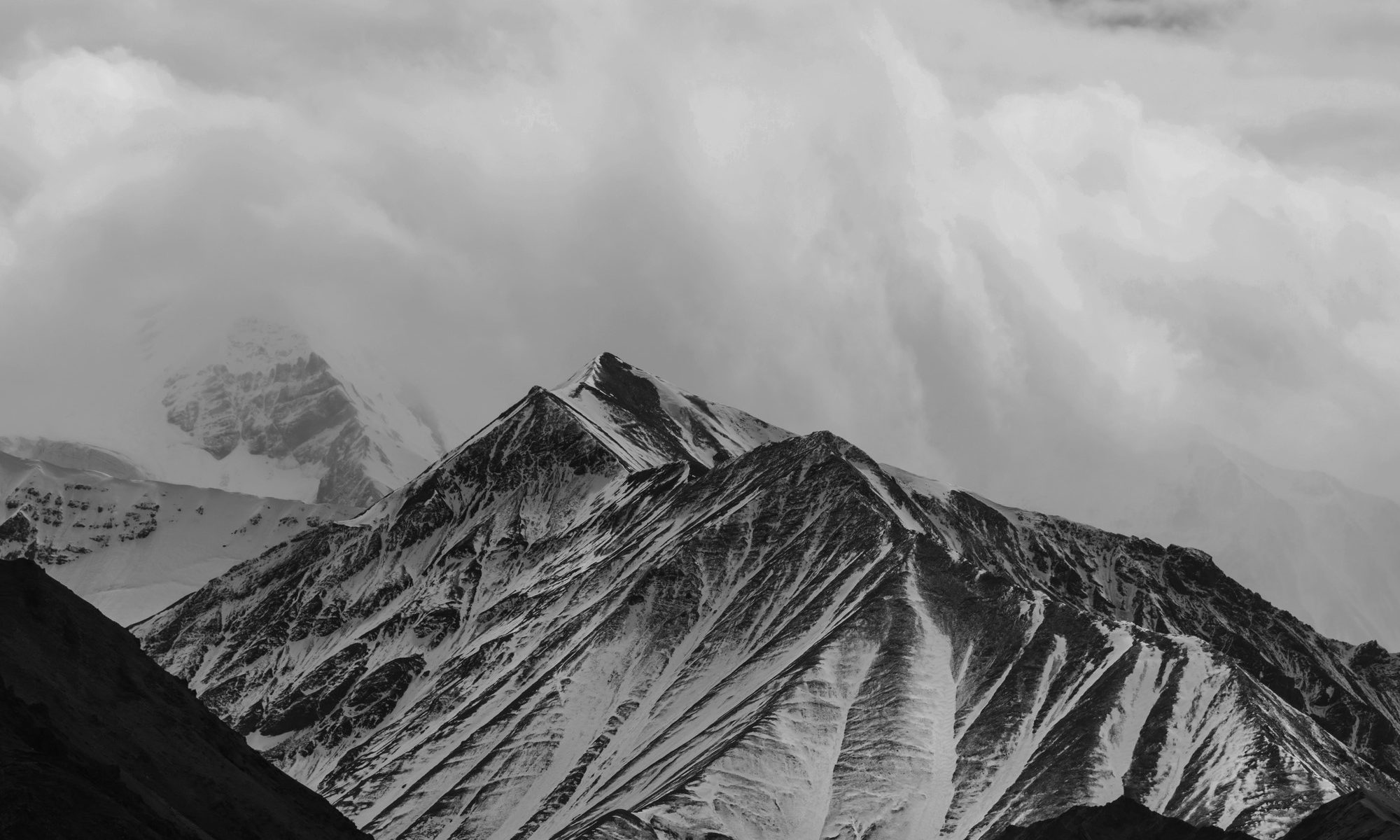 black and white photo of snowy mountains in the clouds