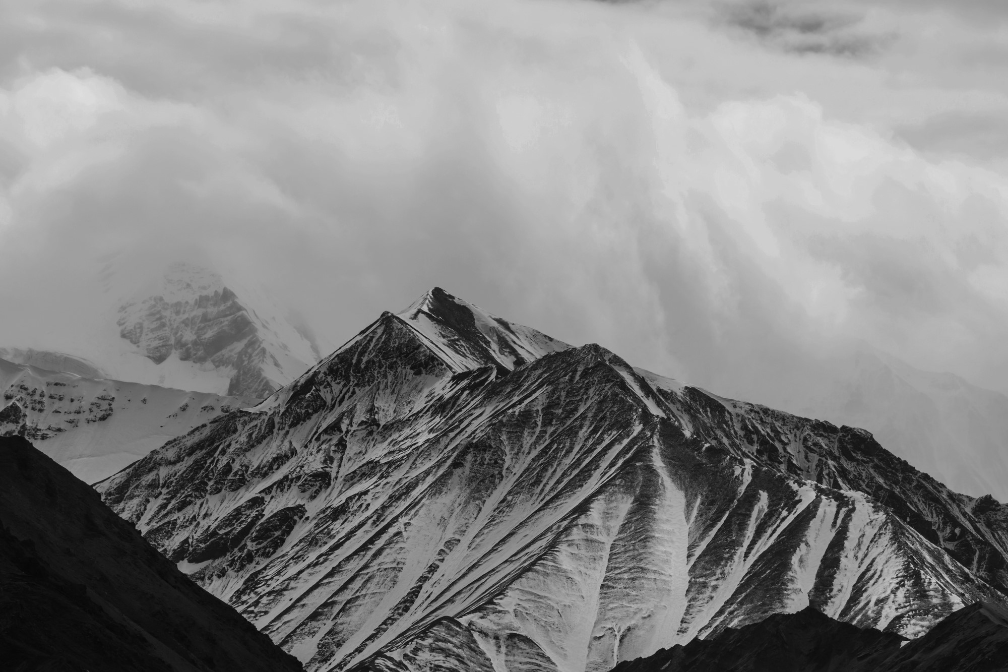 black and white photo of snowy mountains in the clouds