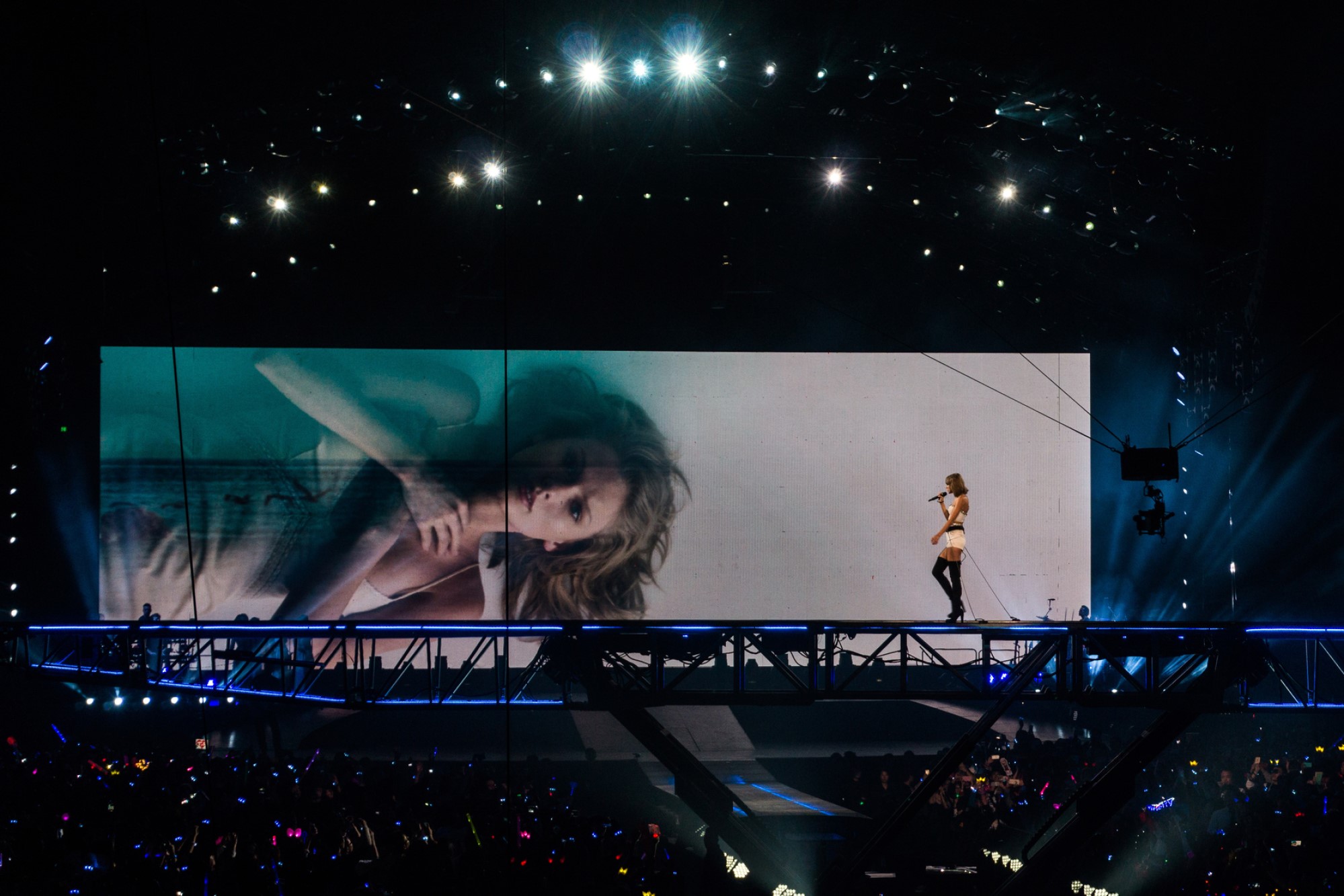 photograph of Taylor Swift performing on stage with image on screen in background