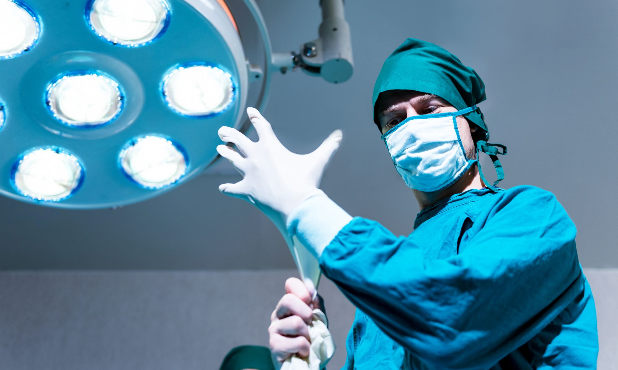 photograph of surgeon in operating room putting on gloves