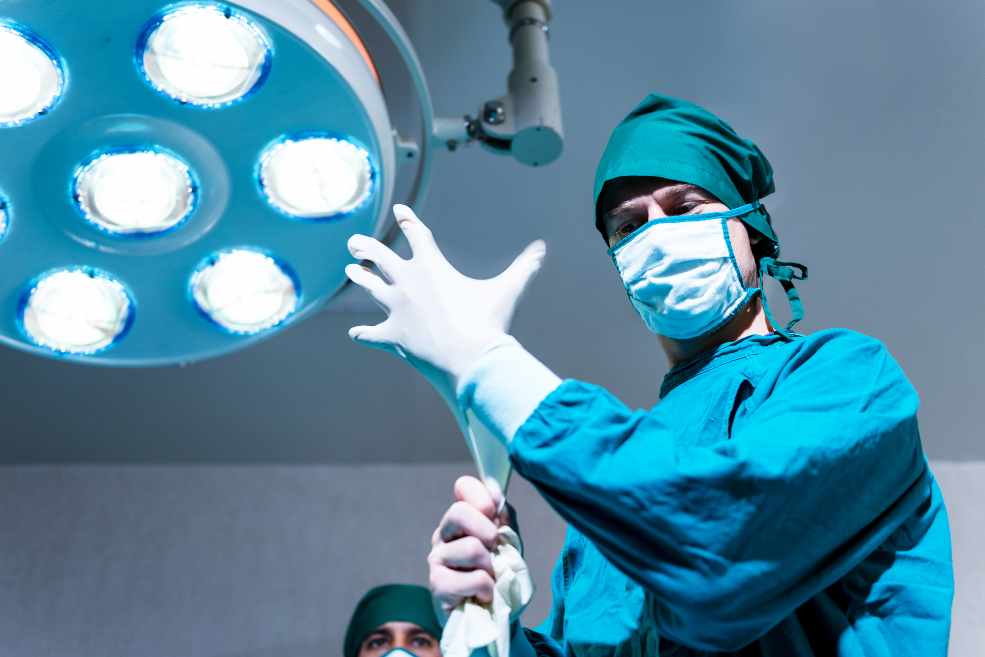 photograph of surgeon in operating room putting on gloves