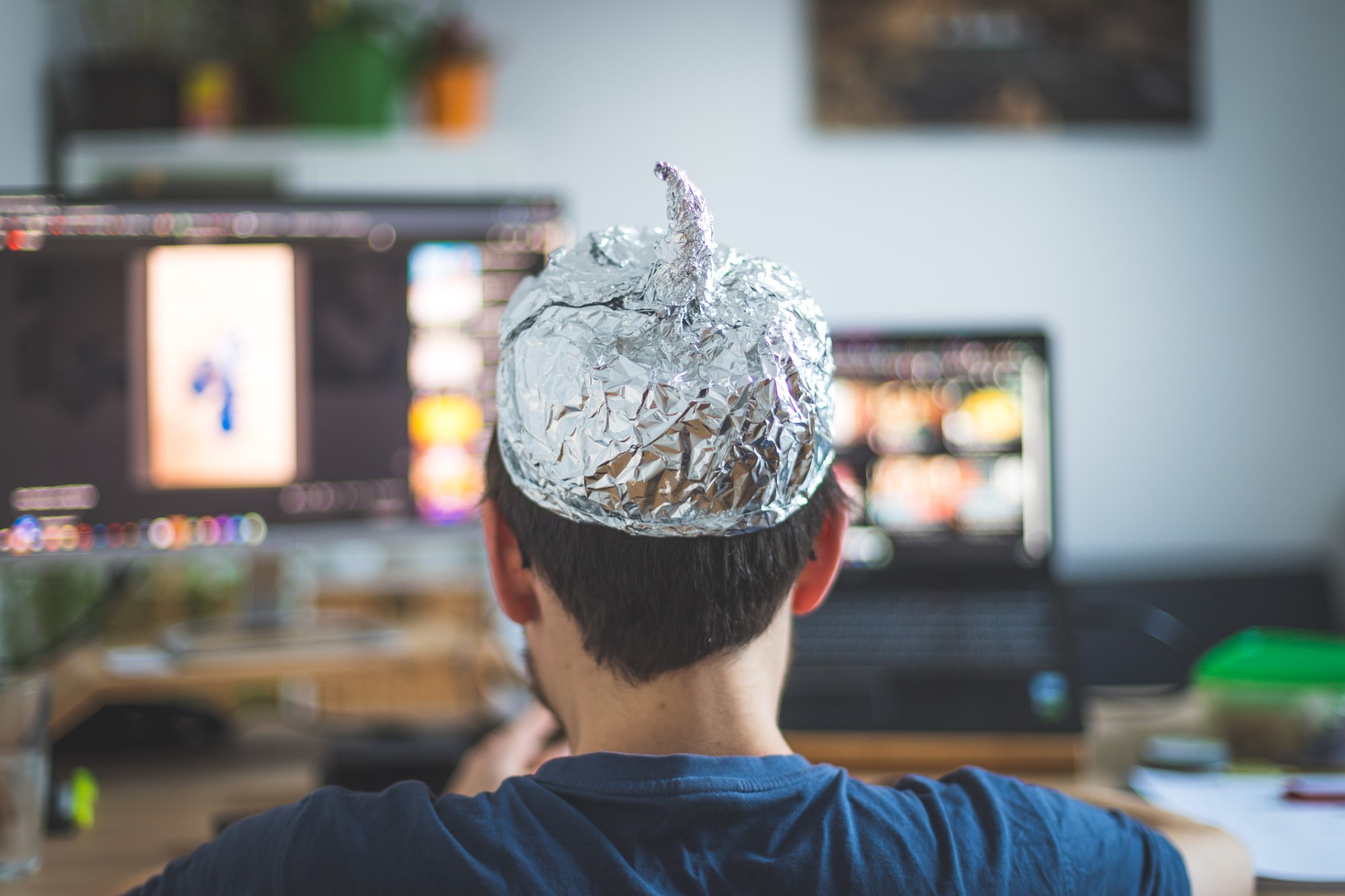 photograph of person in tin foil hat consuming media